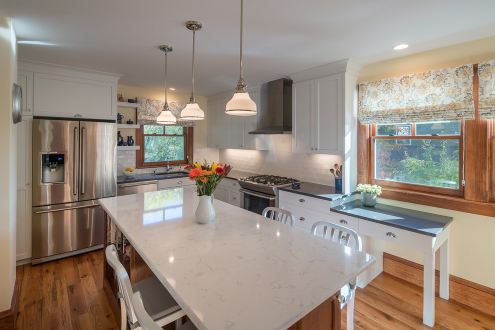 Mid-sized traditional l-shaped separate kitchen in Boston with an undermount sink, flat-panel cabinets, white cabinets, quartz benchtops, white splashback, ceramic splashback, stainless steel appliances, medium hardwood floors and with island.
