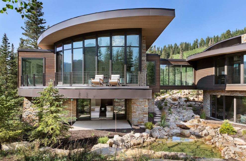 Huge mountain style brown two-story stone and clapboard house exterior photo in Salt Lake City with a shed roof, a metal roof and a brown roof