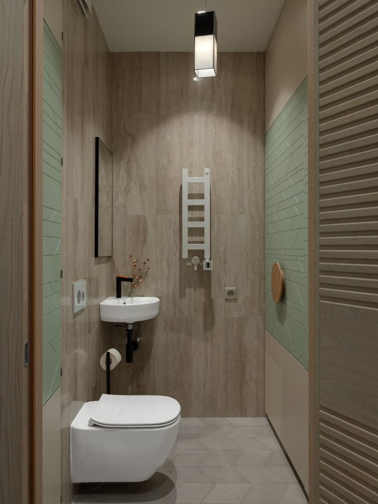 This is an example of a small asian powder room in Moscow with a wall-mount toilet, beige tile, ceramic tile, beige walls, ceramic floors, a wall-mount sink and grey floor.