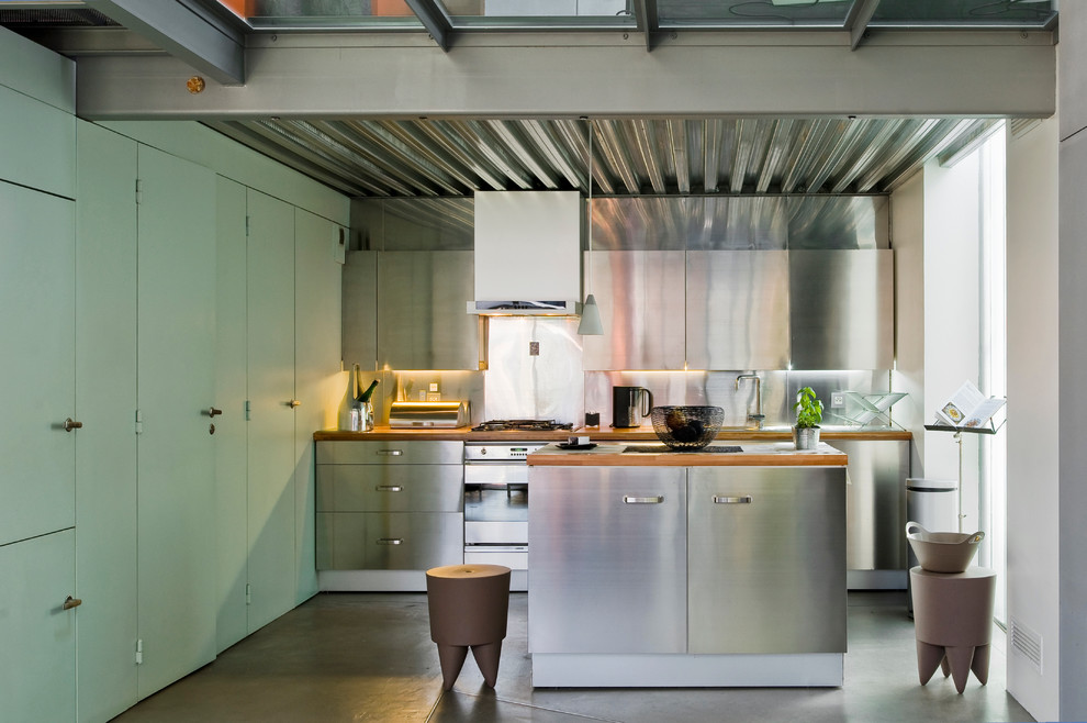 Mid-sized industrial galley open plan kitchen in Paris with stainless steel cabinets and with island.