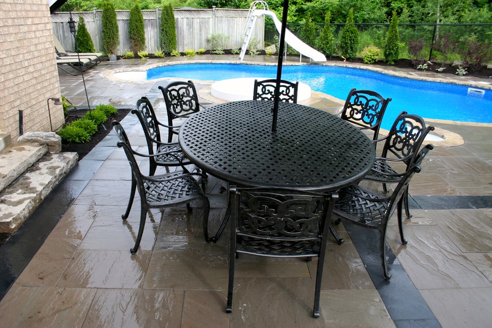 Mid-sized contemporary backyard custom-shaped natural pool in Toronto with a hot tub and natural stone pavers.