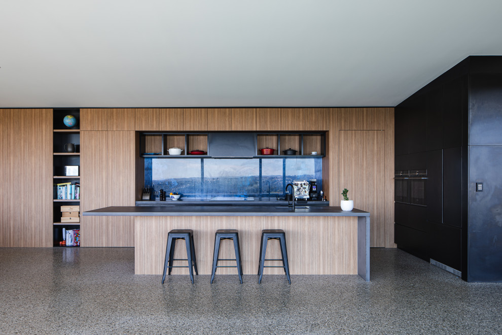 Photo of a modern galley open plan kitchen in Gold Coast - Tweed with an undermount sink, flat-panel cabinets, medium wood cabinets, concrete floors, with island, grey floor and grey benchtop.