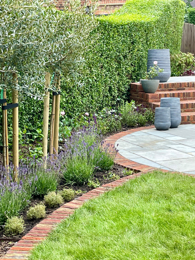 Design ideas for a medium sized traditional back partial sun garden for autumn in London with lawn edging and brick paving.