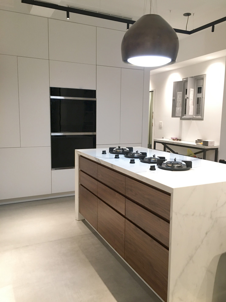 Inspiration for a large contemporary l-shaped eat-in kitchen in New York with an undermount sink, flat-panel cabinets, white cabinets, marble benchtops, white splashback, marble splashback, panelled appliances, ceramic floors, with island, grey floor and white benchtop.
