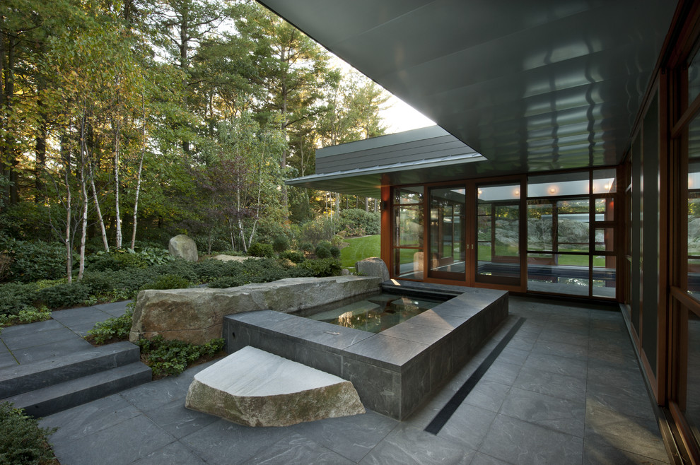 Patio - backyard stone patio idea in Boston with a roof extension