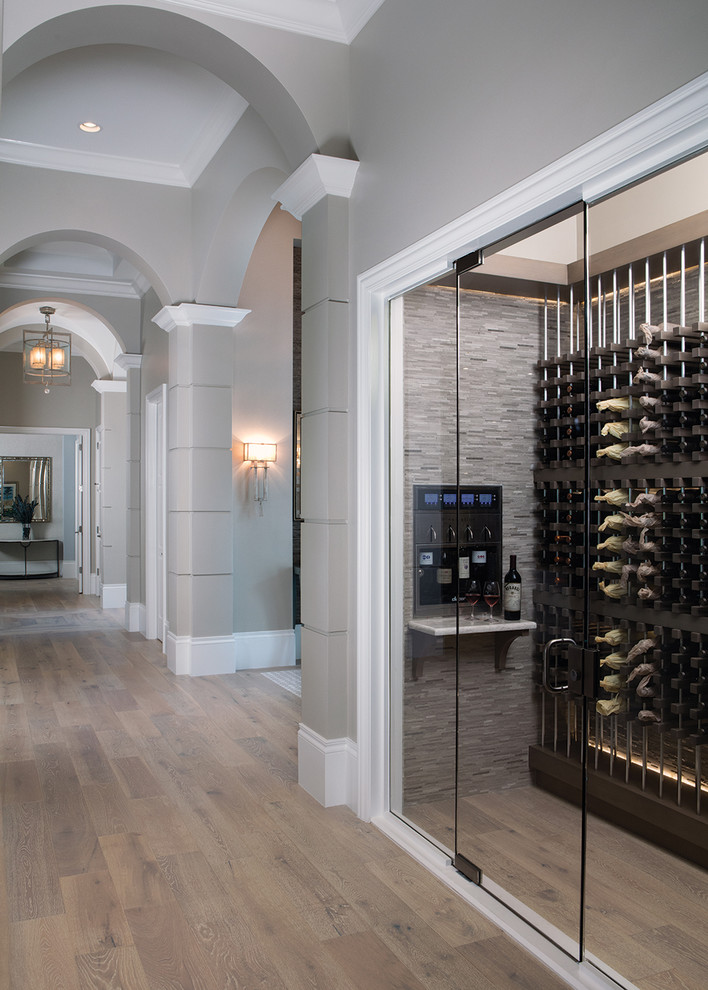 This is an example of a mid-sized transitional wine cellar in Miami with light hardwood floors, storage racks and brown floor.