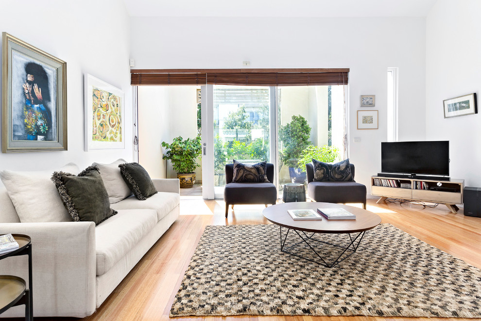 Inspiration for a transitional family room in Melbourne with white walls, light hardwood floors, a freestanding tv and beige floor.