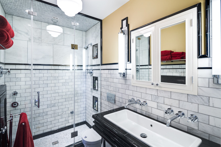 Small transitional 3/4 bathroom in Philadelphia with a trough sink, granite benchtops, a double shower, a wall-mount toilet, white tile, subway tile, marble floors, a hinged shower door, black benchtops, a double vanity and a freestanding vanity.