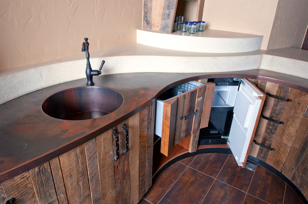 This is an example of a transitional u-shaped seated home bar in Denver with an integrated sink, flat-panel cabinets, distressed cabinets, copper benchtops and porcelain floors.