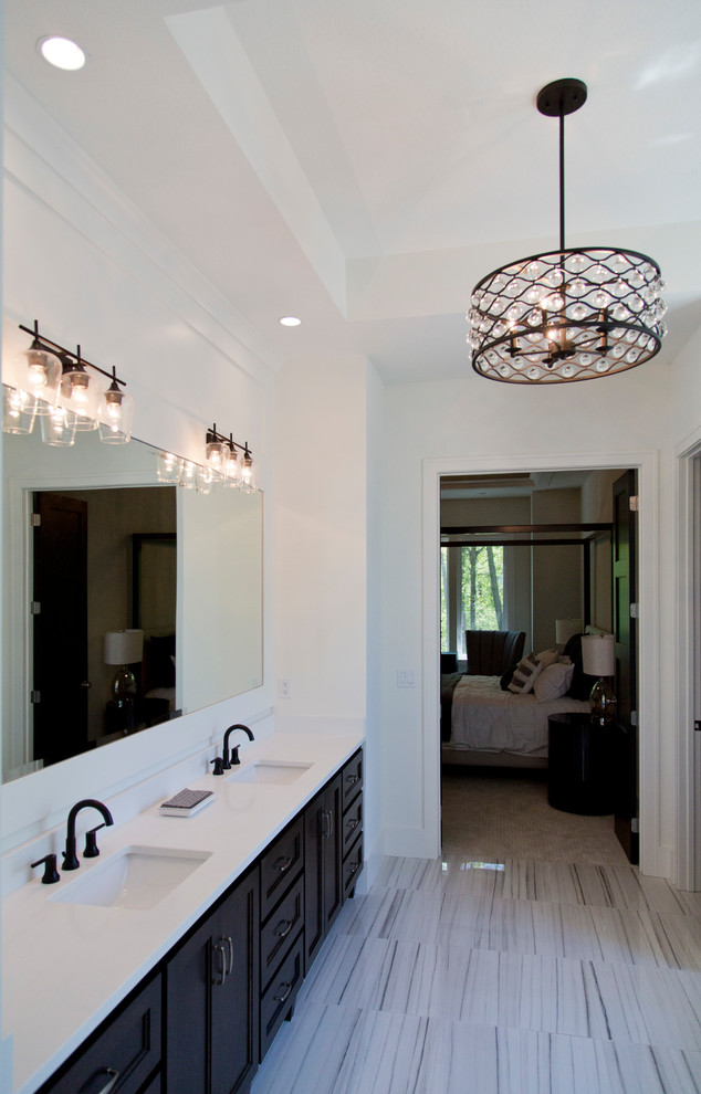 This is an example of a large modern master bathroom in Kansas City with recessed-panel cabinets, black cabinets, a freestanding tub, a corner shower, white walls, ceramic floors, an undermount sink, multi-coloured floor, a hinged shower door and white benchtops.