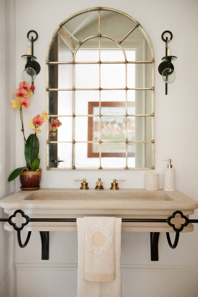 Inspiration for a large mediterranean powder room in Other with a two-piece toilet, beige tile, stone tile, beige walls, a trough sink and limestone floors.
