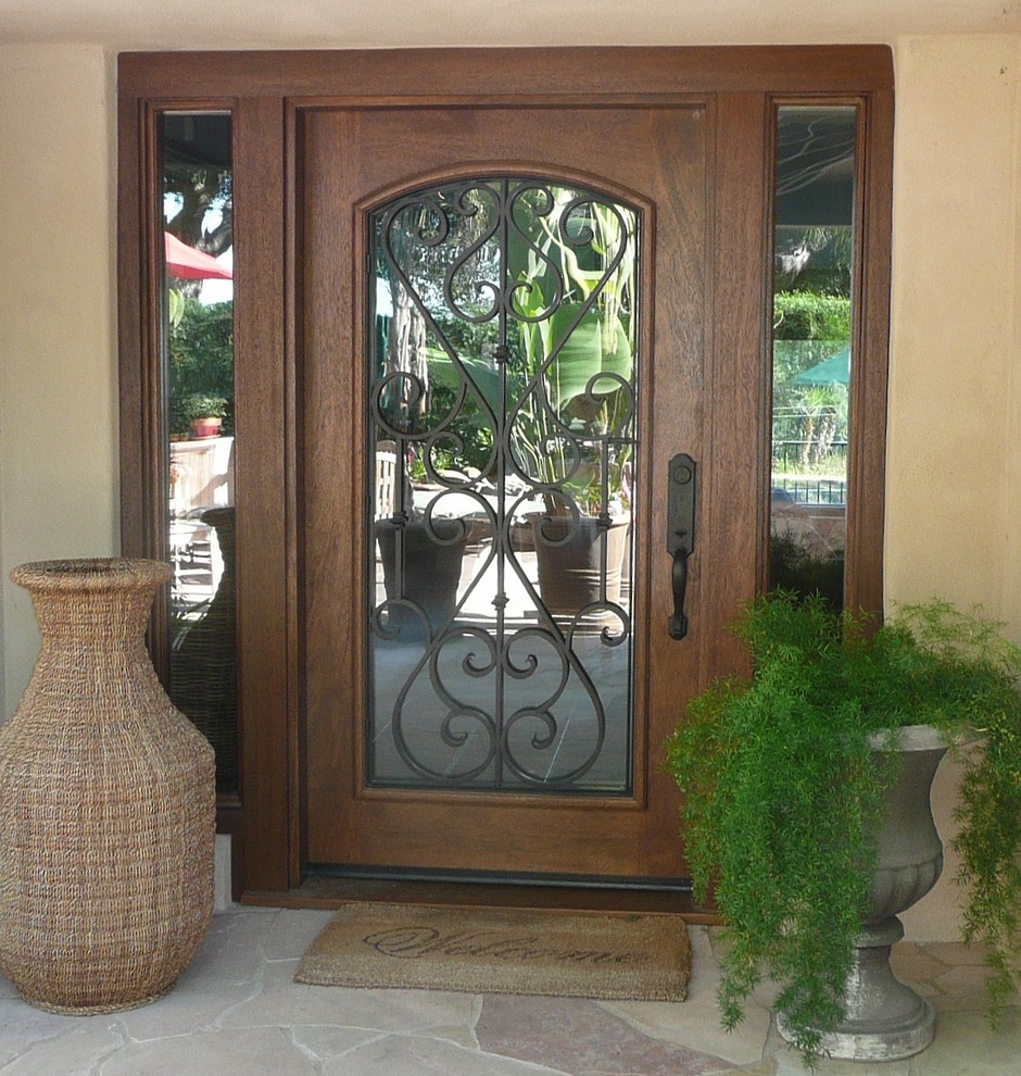 Photo of a mediterranean foyer in San Diego with brown walls, slate floors, a single front door and a medium wood front door.