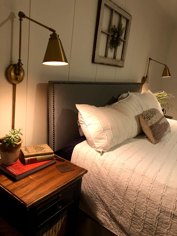 Modelo de dormitorio principal campestre de tamaño medio sin chimenea con paredes blancas, suelo de madera oscura, suelo marrón y boiserie