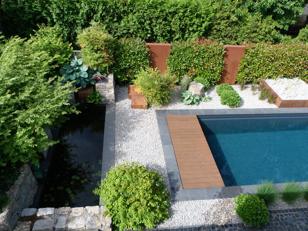 This is an example of a mid-sized modern backyard rectangular lap pool in Frankfurt with decomposed granite.