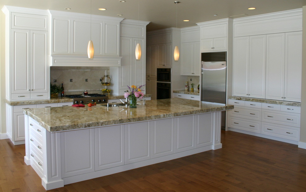 Design ideas for a large transitional l-shaped open plan kitchen in Sacramento with an undermount sink, raised-panel cabinets, white cabinets, granite benchtops, beige splashback, stainless steel appliances, medium hardwood floors and with island.