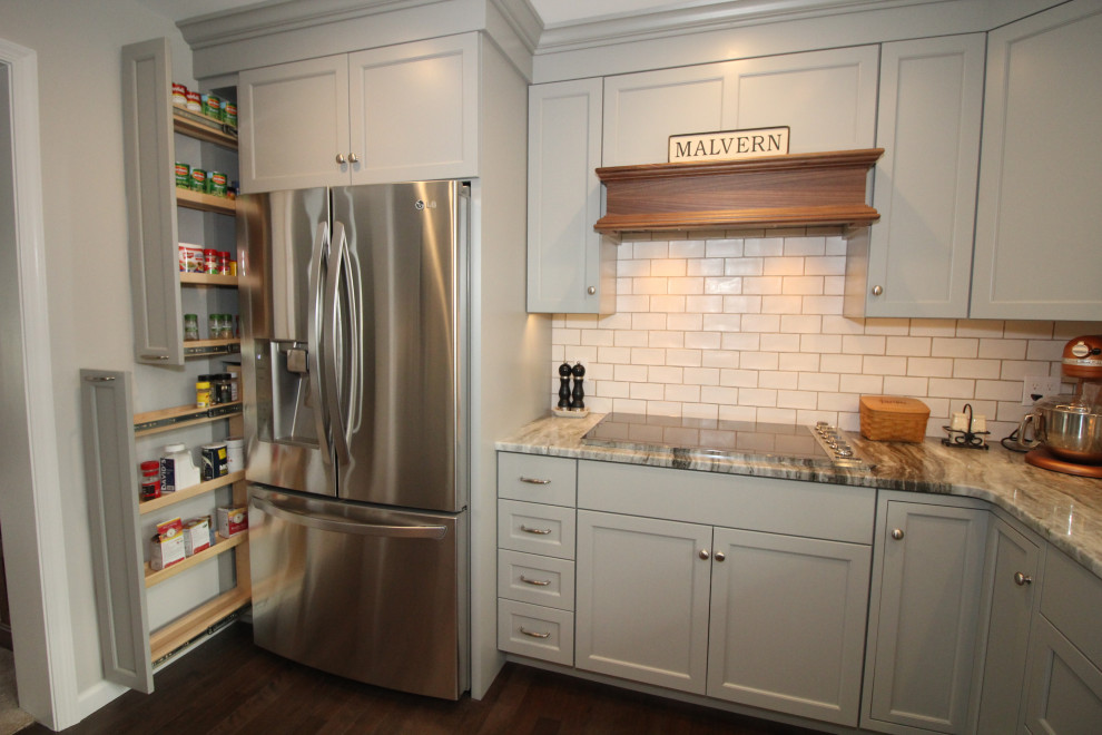 This is an example of a mid-sized traditional u-shaped eat-in kitchen in Philadelphia with a farmhouse sink, flat-panel cabinets, grey cabinets, quartzite benchtops, white splashback, subway tile splashback, stainless steel appliances, dark hardwood floors, a peninsula, brown floor and grey benchtop.
