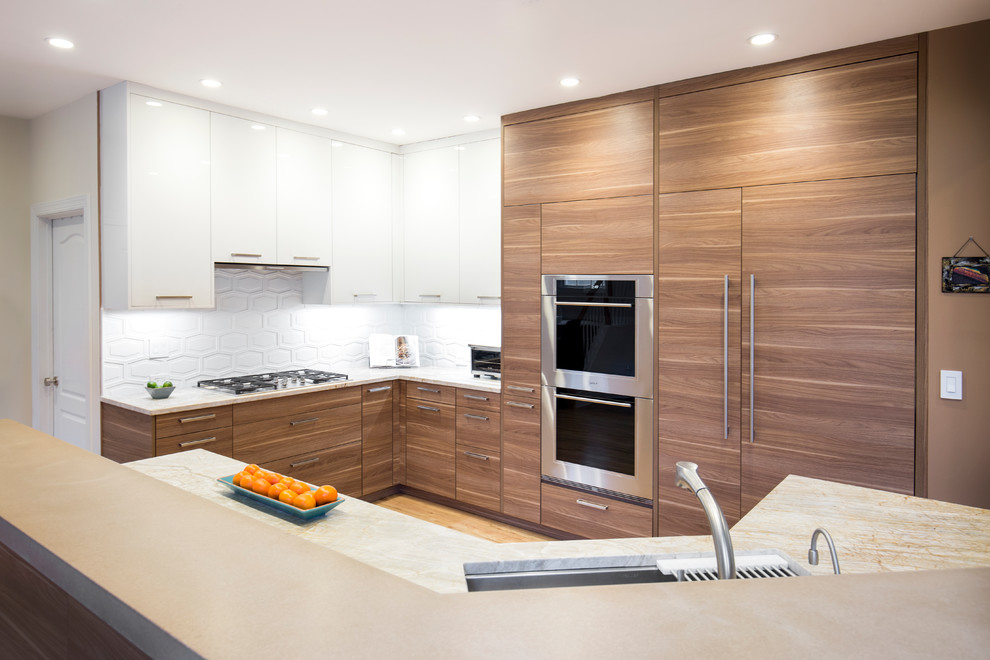 This is an example of a mid-sized contemporary u-shaped open plan kitchen in New York with a single-bowl sink, flat-panel cabinets, medium wood cabinets, quartz benchtops, white splashback, porcelain splashback, stainless steel appliances and light hardwood floors.