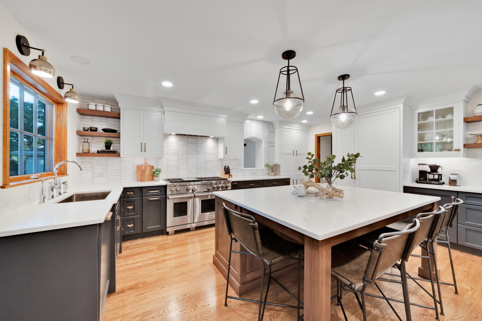 Photo of an expansive transitional l-shaped eat-in kitchen in Columbus with an undermount sink, grey cabinets, quartzite benchtops, white splashback, brick splashback, stainless steel appliances, light hardwood floors, with island, yellow floor and white benchtop.