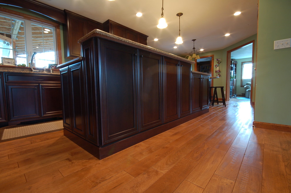 Inspiration for a traditional l-shaped eat-in kitchen in Boston with recessed-panel cabinets, dark wood cabinets, stainless steel appliances, an undermount sink, quartz benchtops and medium hardwood floors.