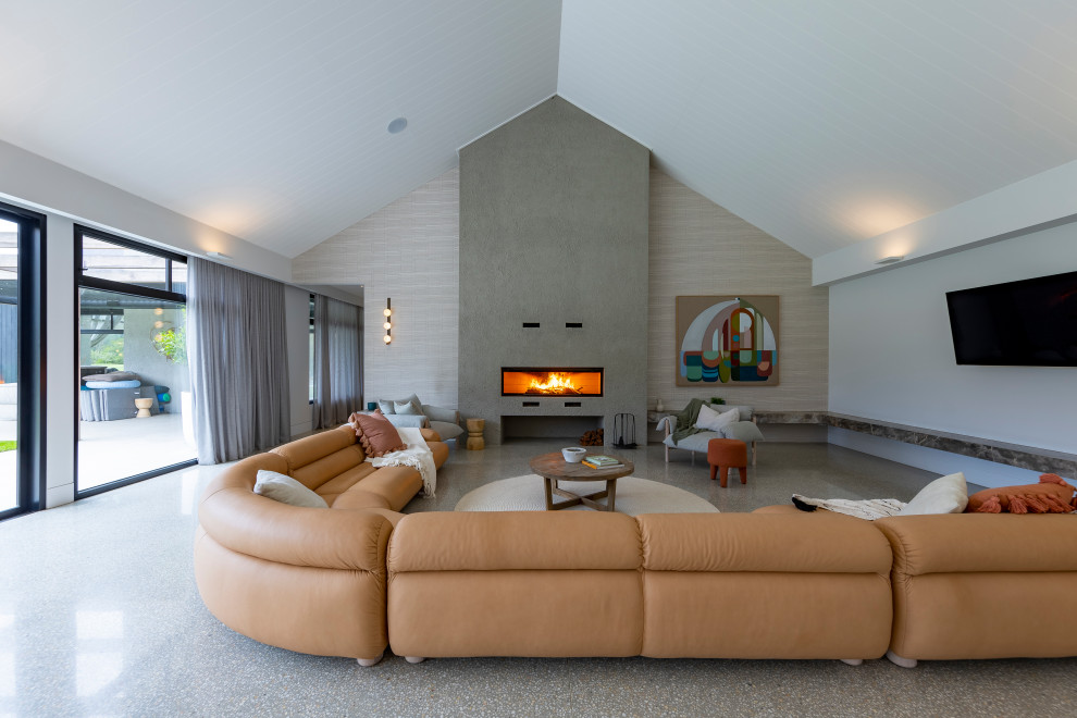 Стильный дизайн: огромная открытая гостиная комната в современном стиле с серыми стенами, бетонным полом и стандартным камином - последний тренд