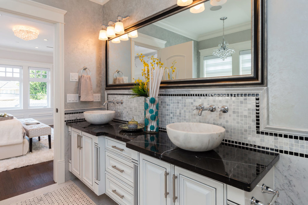 Design ideas for a mid-sized master bathroom in Vancouver with raised-panel cabinets, white cabinets, gray tile, white tile, marble, grey walls, marble floors, a vessel sink, marble benchtops, grey floor and black benchtops.