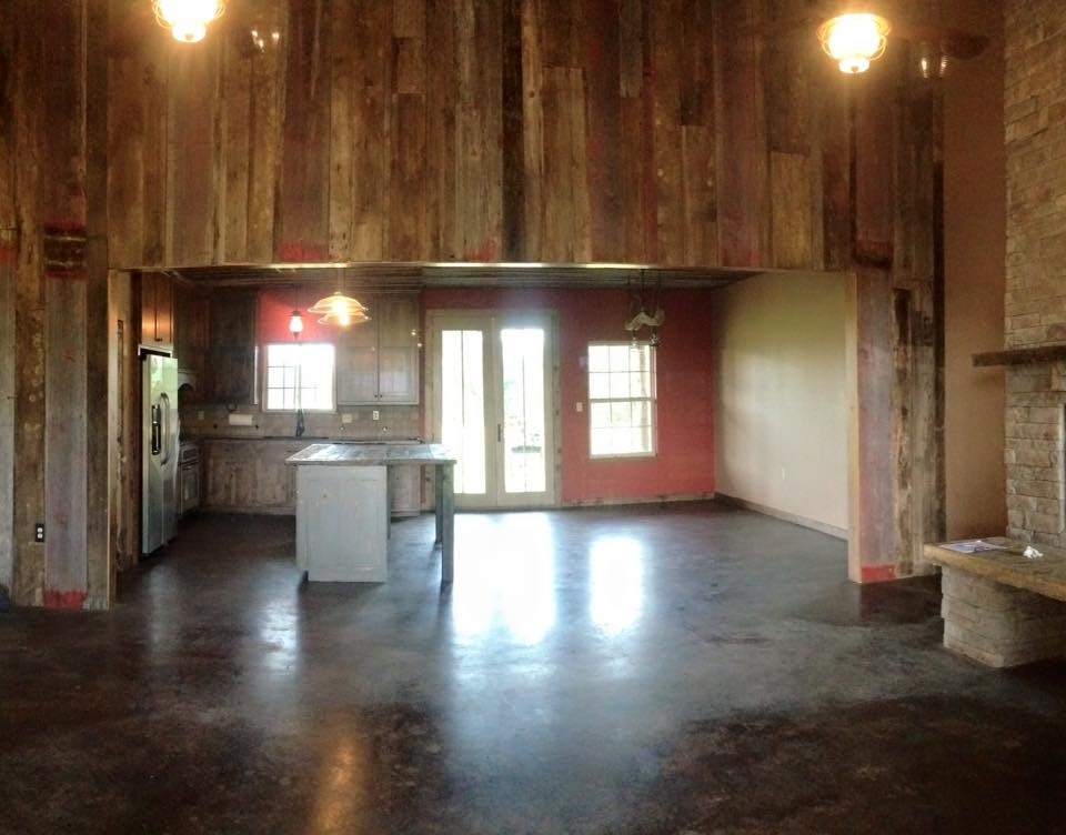 Kitchen - rustic concrete floor kitchen idea with an undermount sink, flat-panel cabinets, medium tone wood cabinets, granite countertops, beige backsplash, stone tile backsplash, stainless steel appliances and an island