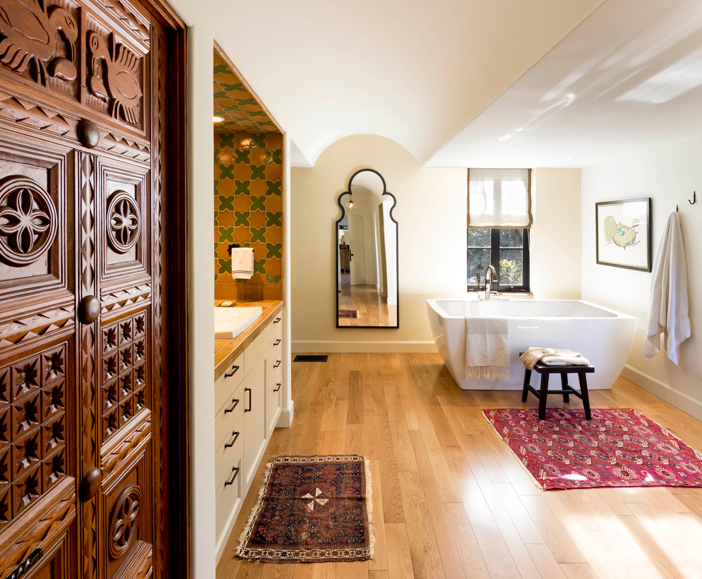 Inspiration for a large mediterranean master multicolored tile and porcelain tile medium tone wood floor freestanding bathtub remodel in Santa Barbara with shaker cabinets, beige cabinets, a two-piece toilet, beige walls, a drop-in sink and tile countertops