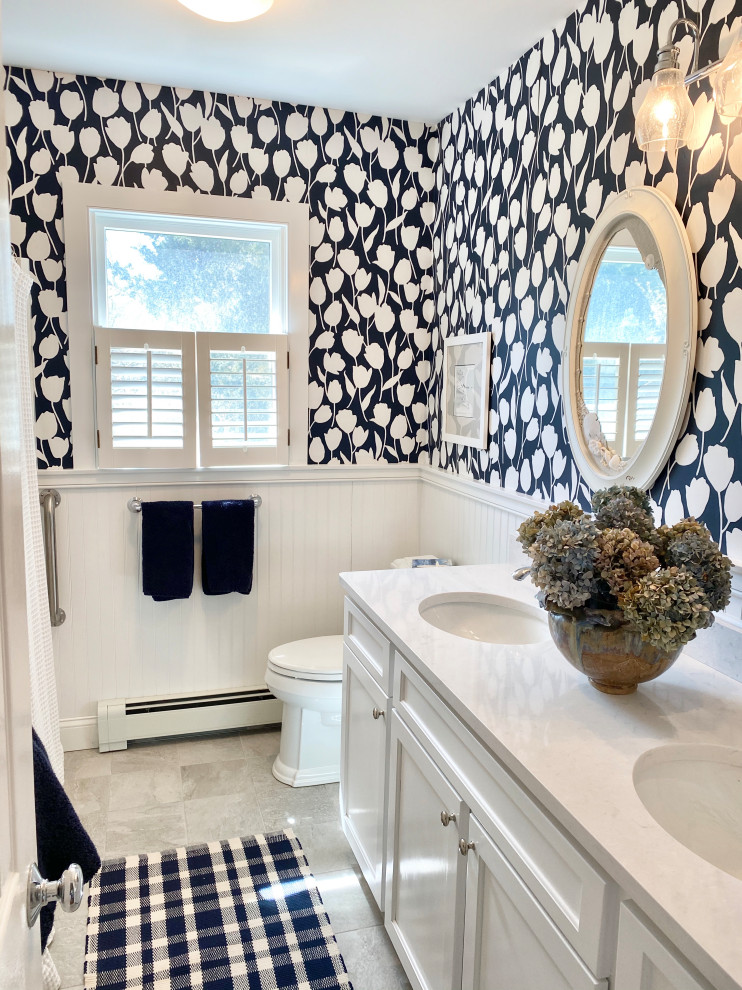 Design ideas for a mid-sized beach style bathroom in Boston with recessed-panel cabinets, white cabinets, a drop-in tub, a shower/bathtub combo, a two-piece toilet, multi-coloured tile, multi-coloured walls, cement tiles, an undermount sink, engineered quartz benchtops, grey floor, a shower curtain, white benchtops, a double vanity, a built-in vanity and wallpaper.