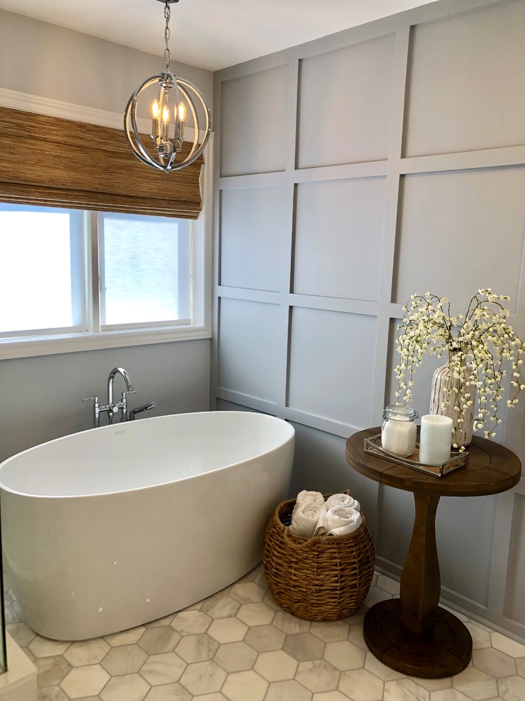 This is an example of a large contemporary master bathroom in Toronto with shaker cabinets, white cabinets, a freestanding tub, a corner shower, a one-piece toilet, gray tile, marble, grey walls, marble floors, an undermount sink, quartzite benchtops, a sliding shower screen and white benchtops.