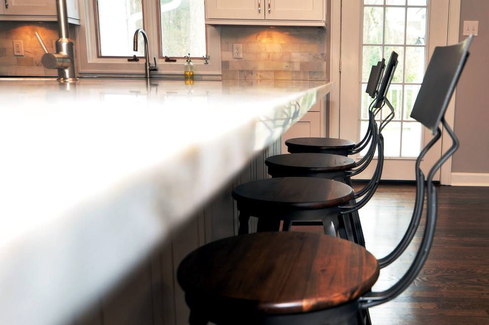 Example of a mid-sized transitional l-shaped medium tone wood floor open concept kitchen design in Atlanta with a double-bowl sink, white cabinets, quartzite countertops, white backsplash, stainless steel appliances and an island