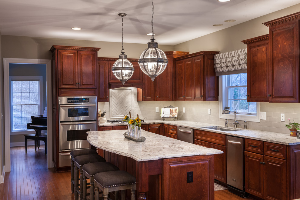 Mid-sized transitional l-shaped dark wood floor and brown floor eat-in kitchen photo in Chicago with an undermount sink, raised-panel cabinets, granite countertops, white backsplash, stainless steel appliances, an island, dark wood cabinets, subway tile backsplash and multicolored countertops