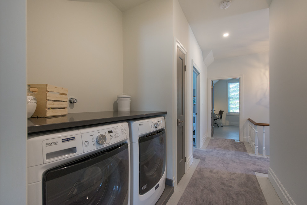 Photo of a small transitional single-wall laundry room in Toronto with granite benchtops, white walls, painted wood floors, a side-by-side washer and dryer and grey floor.