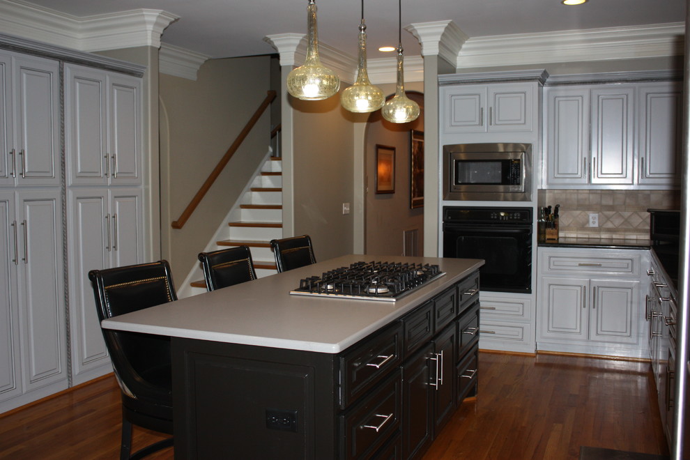 Inspiration for a large transitional u-shaped light wood floor eat-in kitchen remodel with a double-bowl sink, raised-panel cabinets, gray cabinets, quartz countertops, beige backsplash, ceramic backsplash, stainless steel appliances and an island