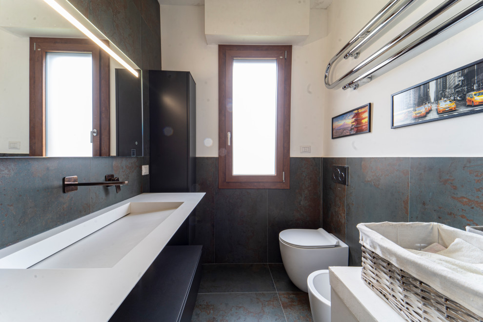 This is an example of an expansive modern master bathroom in Florence with a curbless shower, a two-piece toilet, multi-coloured tile, porcelain tile, porcelain floors, a wall-mount sink, solid surface benchtops, an open shower, white benchtops, a single vanity and a floating vanity.