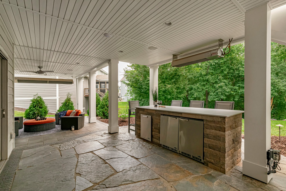 Inspiration for a large craftsman backyard stone patio kitchen remodel in Minneapolis with a roof extension