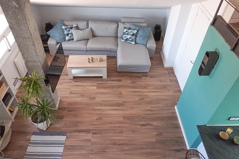 Imagen de sala de estar tipo loft industrial de tamaño medio sin chimenea con paredes blancas, suelo laminado, televisor en una esquina y suelo marrón