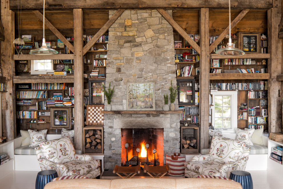 Aménagement d'un salon montagne ouvert avec une bibliothèque ou un coin lecture, une cheminée standard, un manteau de cheminée en pierre et poutres apparentes.