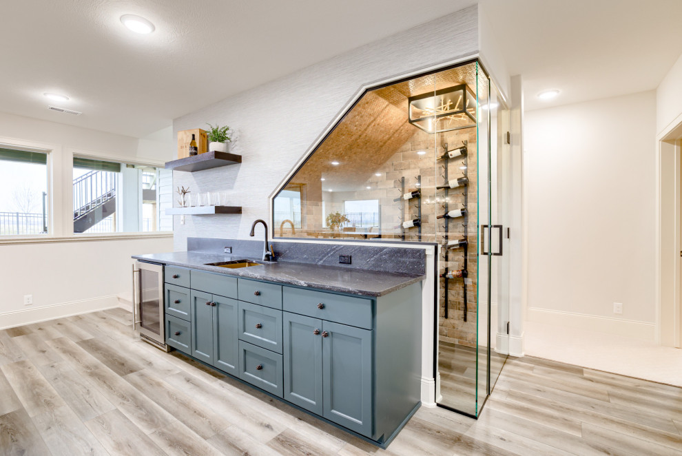 Traditional single-wall wet bar in Omaha with an undermount sink, shaker cabinets, granite benchtops, medium hardwood floors and black benchtop.