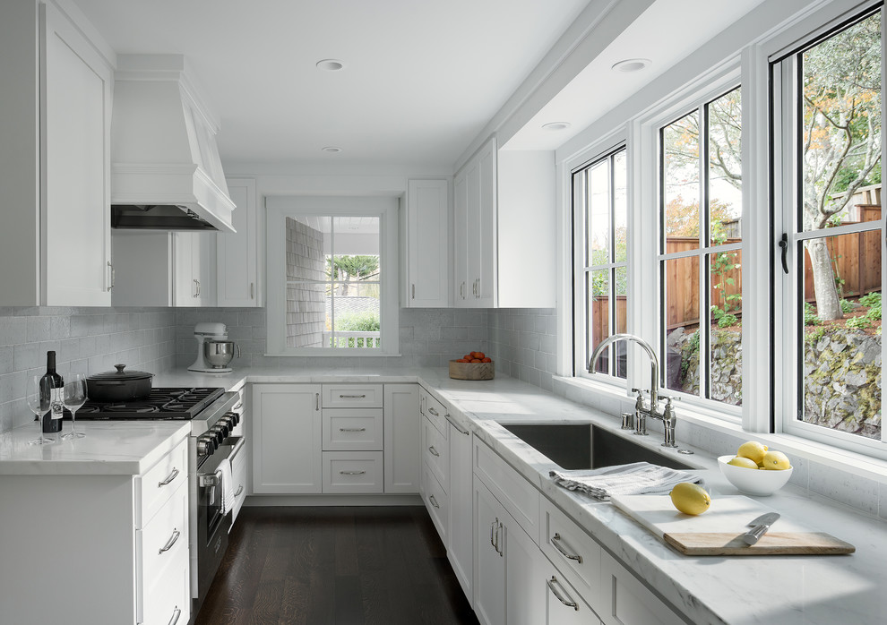 Transitional u-shaped dark wood floor and brown floor kitchen photo in San Francisco with an undermount sink, shaker cabinets, white cabinets, white backsplash, subway tile backsplash, stainless steel appliances and no island
