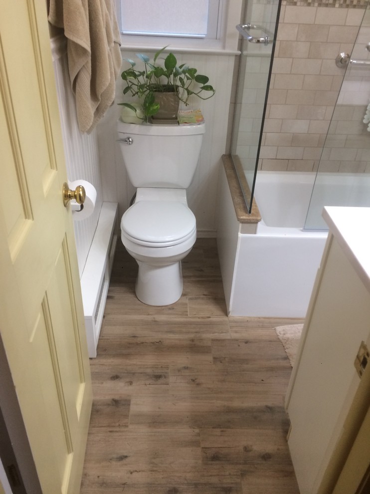 Photo of a small arts and crafts 3/4 bathroom in New York with white cabinets, a corner tub, a shower/bathtub combo, a two-piece toilet, beige tile, brown tile, stone tile, beige walls, ceramic floors, a wall-mount sink, solid surface benchtops, beige floor and a hinged shower door.