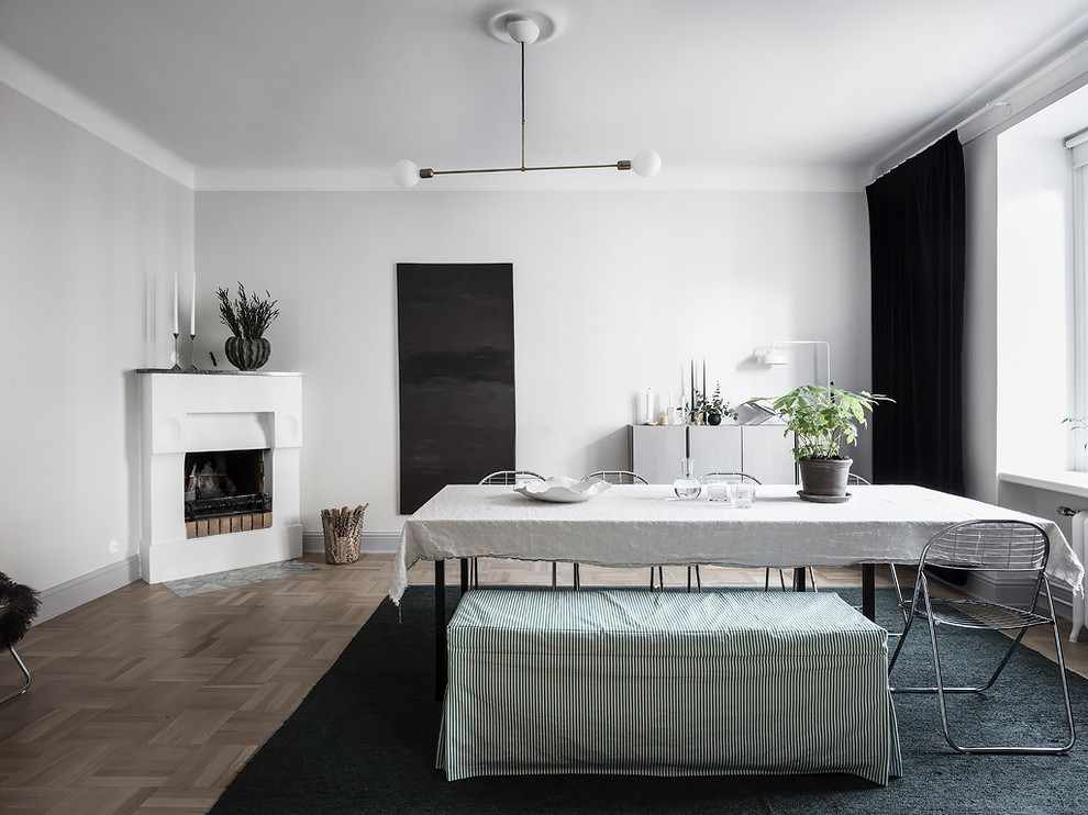 Photo of a mid-sized scandinavian separate dining room in Gothenburg with white walls, medium hardwood floors, a corner fireplace, a plaster fireplace surround and beige floor.