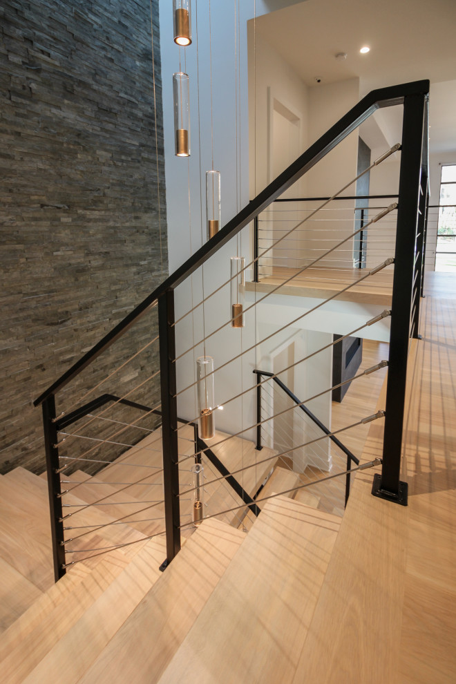 Foto de escalera suspendida ecléctica grande con escalones de madera, barandilla de metal y ladrillo