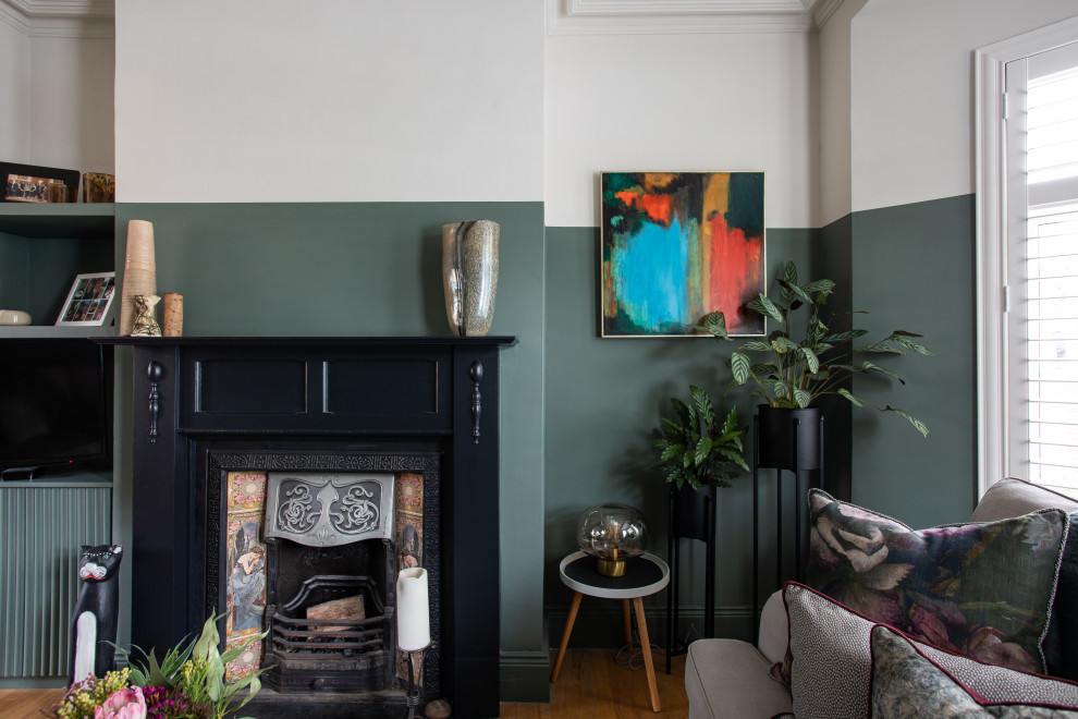 Mittelgroßes Klassisches Wohnzimmer mit grüner Wandfarbe, braunem Holzboden, Kamin, Kaminumrandung aus Holz und Multimediawand in Belfast