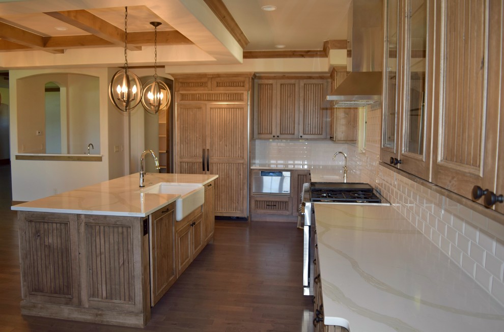 Country l-shaped open plan kitchen in Denver with a farmhouse sink, beaded inset cabinets, medium wood cabinets, quartz benchtops, white splashback, subway tile splashback, stainless steel appliances and with island.