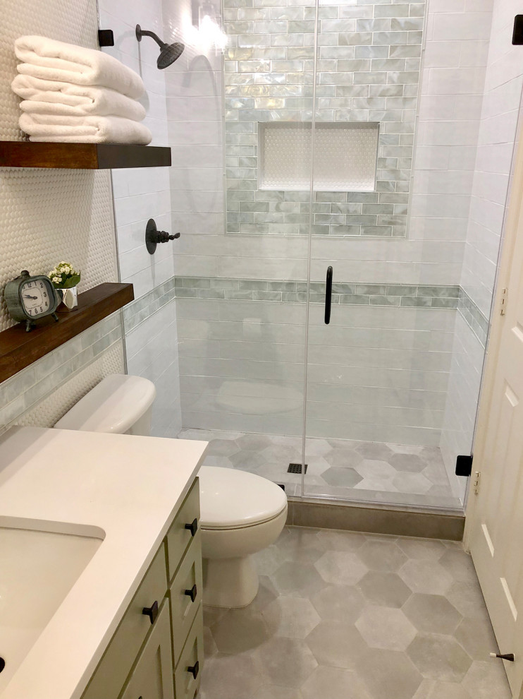 This is an example of a small country bathroom in Dallas with shaker cabinets, a one-piece toilet, white tile, glass tile, green walls, porcelain floors, an undermount sink, engineered quartz benchtops, grey floor, a hinged shower door and white benchtops.