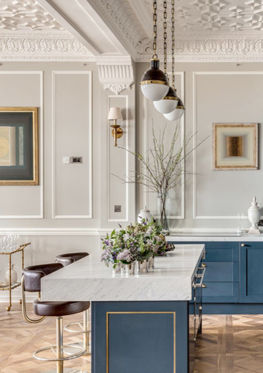 Example of a large classic single-wall medium tone wood floor and multicolored floor open concept kitchen design in London with shaker cabinets, blue cabinets, marble countertops, paneled appliances, an island and multicolored countertops
