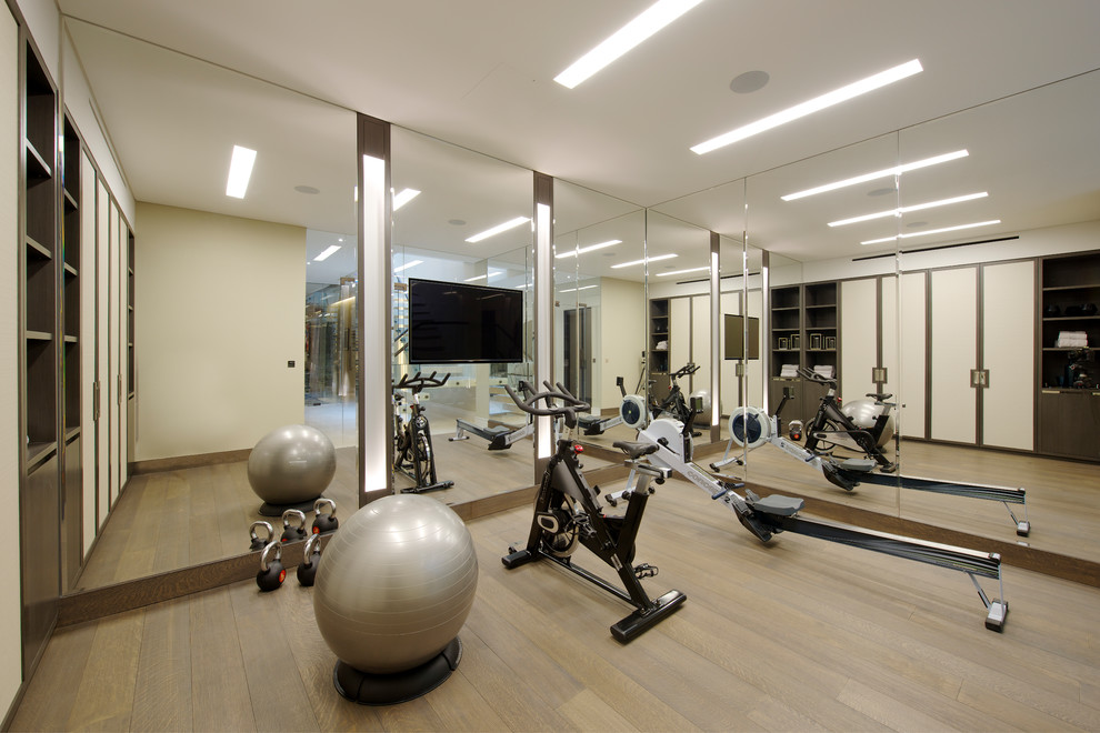 Inspiration for a mid-sized contemporary multipurpose gym in London with beige walls, medium hardwood floors, brown floor and coffered.