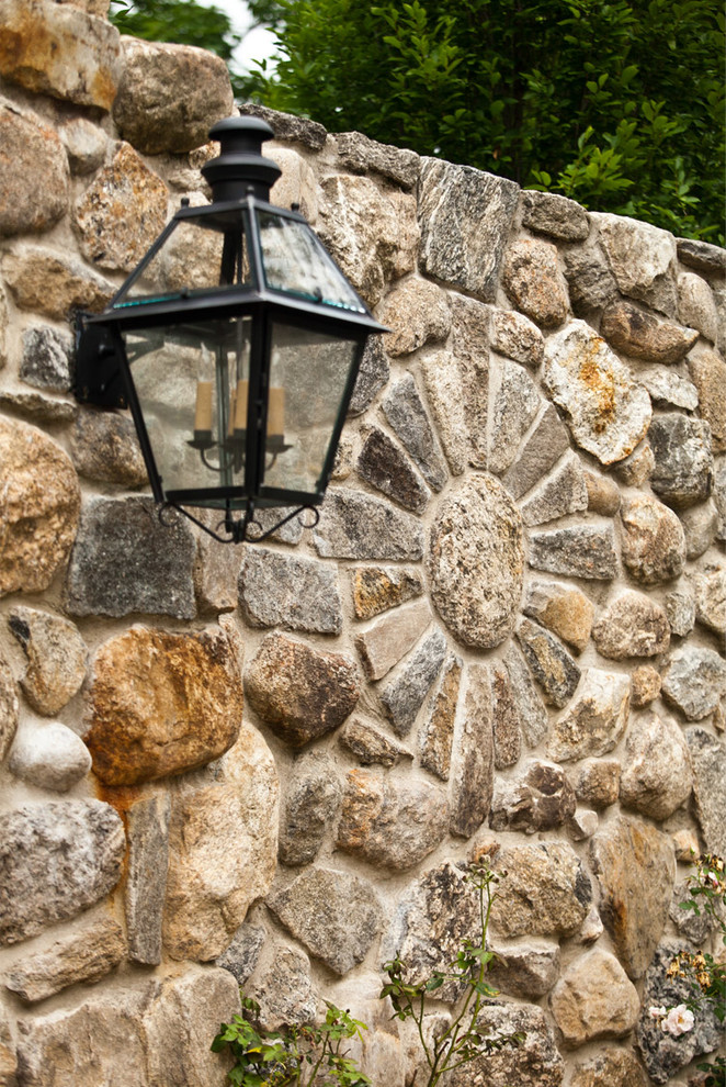 This is an example of a large rustic full sun front yard stone retaining wall landscape in New York for summer.