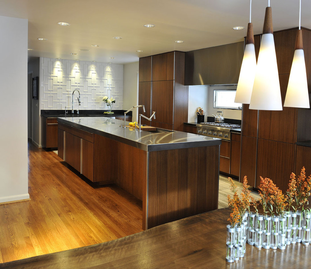 Inspiration for a modern l-shaped eat-in kitchen in Cincinnati with a single-bowl sink, flat-panel cabinets, medium wood cabinets, stainless steel benchtops, white splashback, ceramic splashback and stainless steel appliances.