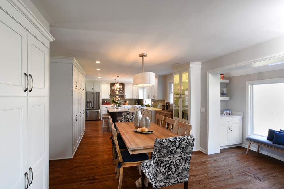 Example of a transitional l-shaped medium tone wood floor eat-in kitchen design in Orange County with an island, shaker cabinets, white cabinets, marble countertops, gray backsplash, glass tile backsplash, stainless steel appliances and a double-bowl sink